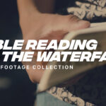 Man reading the Bible and praying near a waterfall in a peaceful outdoor setting.