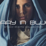 Woman dressed in blue biblical clothing posing as Mary in reverent, serene Christmas stock photos.