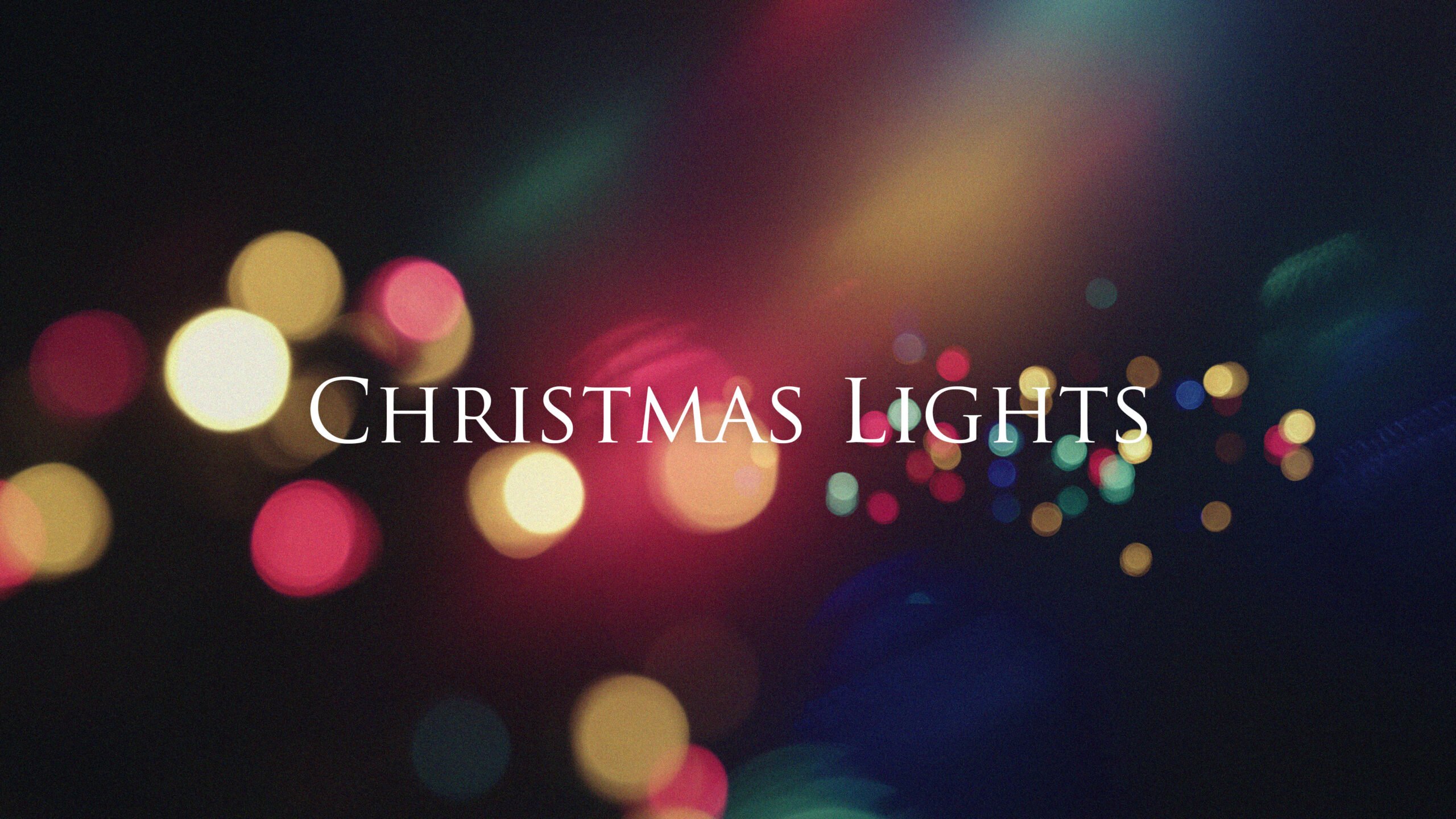 Beautiful Christmas worship background featuring soft defocused colorful bokeh lights in warm gold, pink, red, blue, and teal creating magical holiday atmosphere with elegant white "Christmas Lights" serif typography centered on dark backdrop