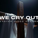 A wooden cross draped with white cloth, lit dramatically in a dark space, symbolizing prayer and hope during Easter.